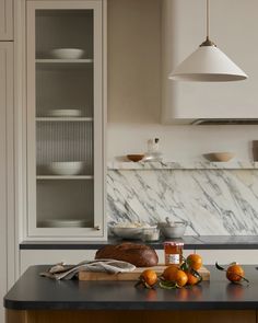 a kitchen with marble counter tops and white cupboards next to a wooden cutting board