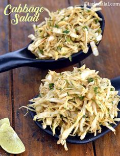 two black spoons filled with coleslaw salad on top of a wooden table