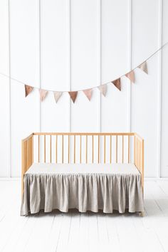 a baby crib with a blanket on it and bunting in front of the crib