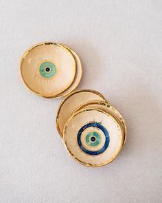 three bowls with blue and green designs on them sitting on a white tableclothed surface