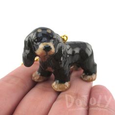 a small black and tan dog figurine sitting on someone's hand