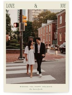 a couple walking across a street in front of a traffic light with the words love and joy written on it