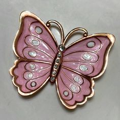 a pink butterfly brooch sitting on top of a table