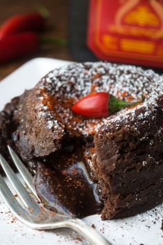 a piece of chocolate cake with powdered sugar on top and a fork in the foreground