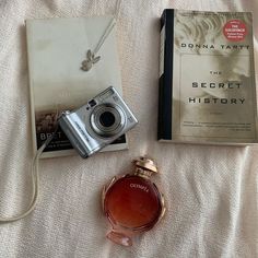 a camera, book and perfume on a bed