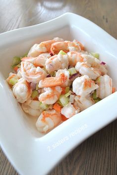 a square white bowl filled with shrimp and celery