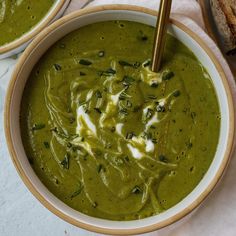 two bowls filled with green soup on top of a table