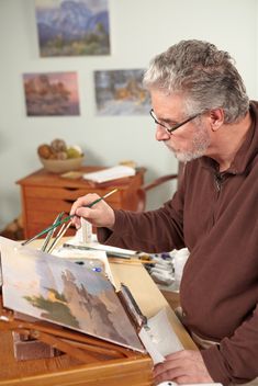 an older man is painting in his living room