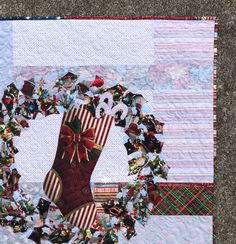 a quilted christmas stocking hanging on the side of a wall with decorations around it