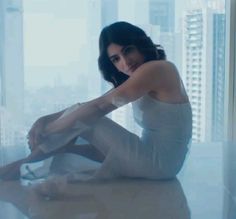 a woman sitting on the floor in front of a window