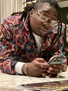 a man with dreadlocks looking at his cell phone while sitting at a table