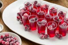 there are many glasses filled with red liquid on the table next to some plates and bowls