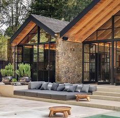 an outdoor living area with couches and tables next to a pool in front of a house