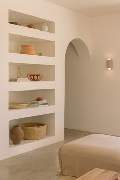 a room with white walls and shelves filled with vases, bowls and other items