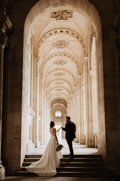 a bride and groom are standing on the stairs in an old building with stone arches