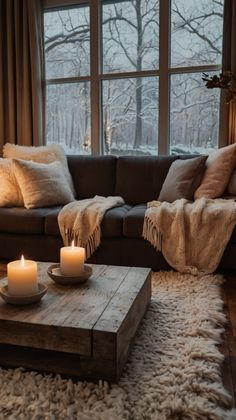 a living room with a couch, coffee table and two candles in front of a window