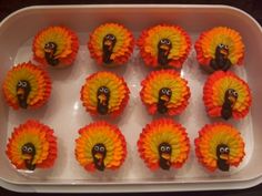 cupcakes decorated with orange and yellow flowers are arranged in the shape of turkey heads