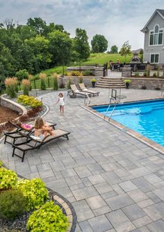 a backyard with a swimming pool surrounded by landscaping