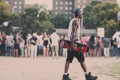 a man walking with a skateboard in his hand while people are standing around him