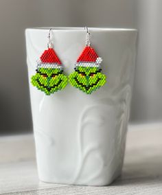 the grin face beaded earrings are sitting on a cup