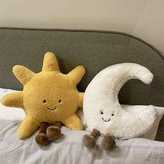 two stuffed animals sitting on top of a bed next to each other in front of a pillow