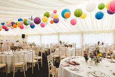 tables and chairs are set up in a tent with paper lanterns hanging from the ceiling