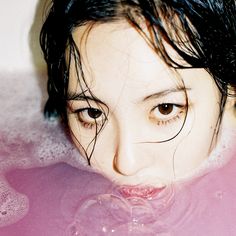 a woman is in the bathtub with her eyes wide open and water around her