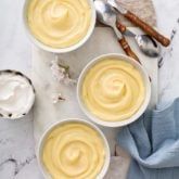 three white bowls filled with cream on top of a marble counter next to spoons