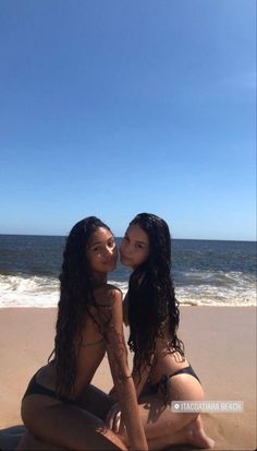 two women sitting on the beach kissing each other