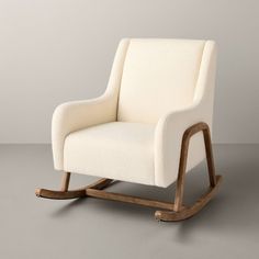 a white rocking chair sitting on top of a gray floor