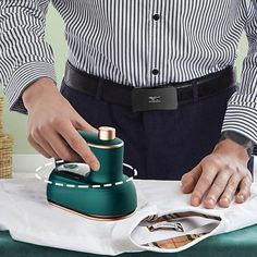 a man is ironing his shirt on an ironing board while wearing a striped shirt