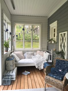 a room with a couch, chair and window on the side of the house that is decorated in shades of blue and white