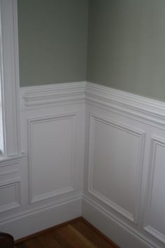 the corner of a room with white waives and wood flooring, painted green