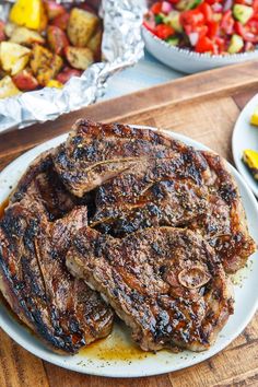 steak on a plate with potatoes and fruit in the background