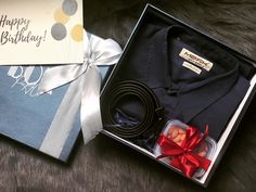 an open box with a tie, shirt and other items in it on a fur surface