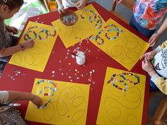 children are sitting at a table making crafts