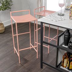 two pink bar stools sitting on top of a white counter next to a wine rack