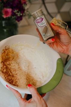 two hands holding a bowl full of rice and seasoning next to a bottle of deodorant