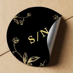 a close up of a black and gold plate with the word s n on it