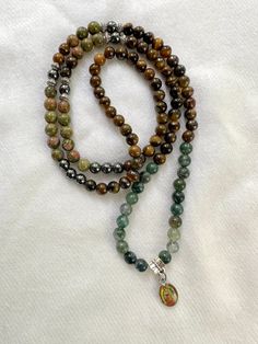 Elastic and mixed gemstome mala with the image of the Lady of Guadalupe. Gemstones are: Tiger Eye, Hematite, Unakite jasper and Moss Agate Can be wrapped around your wrist and worn as a bracelet. Comes in a velvet bag with a mini charm for storage and care. Information card also included. FROM MY SACRED SPACE TO YOURS: Every product goes through a cleansing and Reiki energy ritual the moment I prepare your order. Unakite Jasper, Wrist Mala, Information Card, Lady Of Guadalupe, Reiki Energy, Mini Charm, Velvet Bag, The Lady, Sacred Space