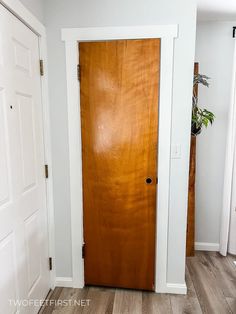 a wooden door in the corner of a white room with wood flooring and hard wood floors