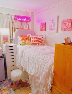 a white bed sitting in a bedroom next to a dresser and window with pink lights