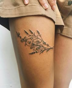 a woman's thigh with flowers and leaves tattoo on her leg, next to the words tattoospiraton