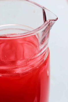 a pitcher filled with red liquid sitting on top of a table