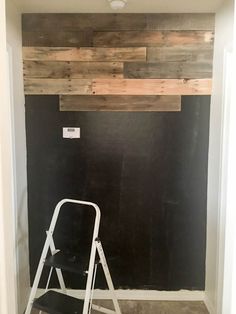 a ladder is sitting in front of a black wall with wood planks on it