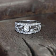 a wedding ring on top of a piece of wood with diamonds in the center and sides