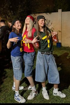 three young women standing next to each other on top of a grass covered field at night