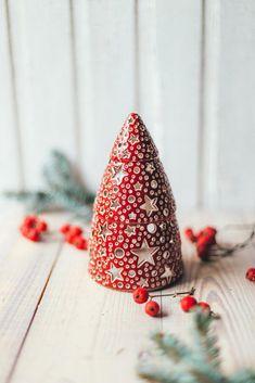 a red and white christmas hat sitting on top of a wooden table next to berries