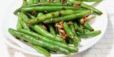 a white plate topped with green beans covered in seasoning and nuts on top of it