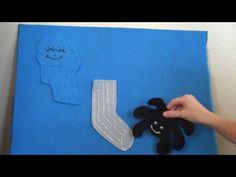 someone is making an art project with felt and scissors on a blue canvas, which has a sock shaped like a person's foot